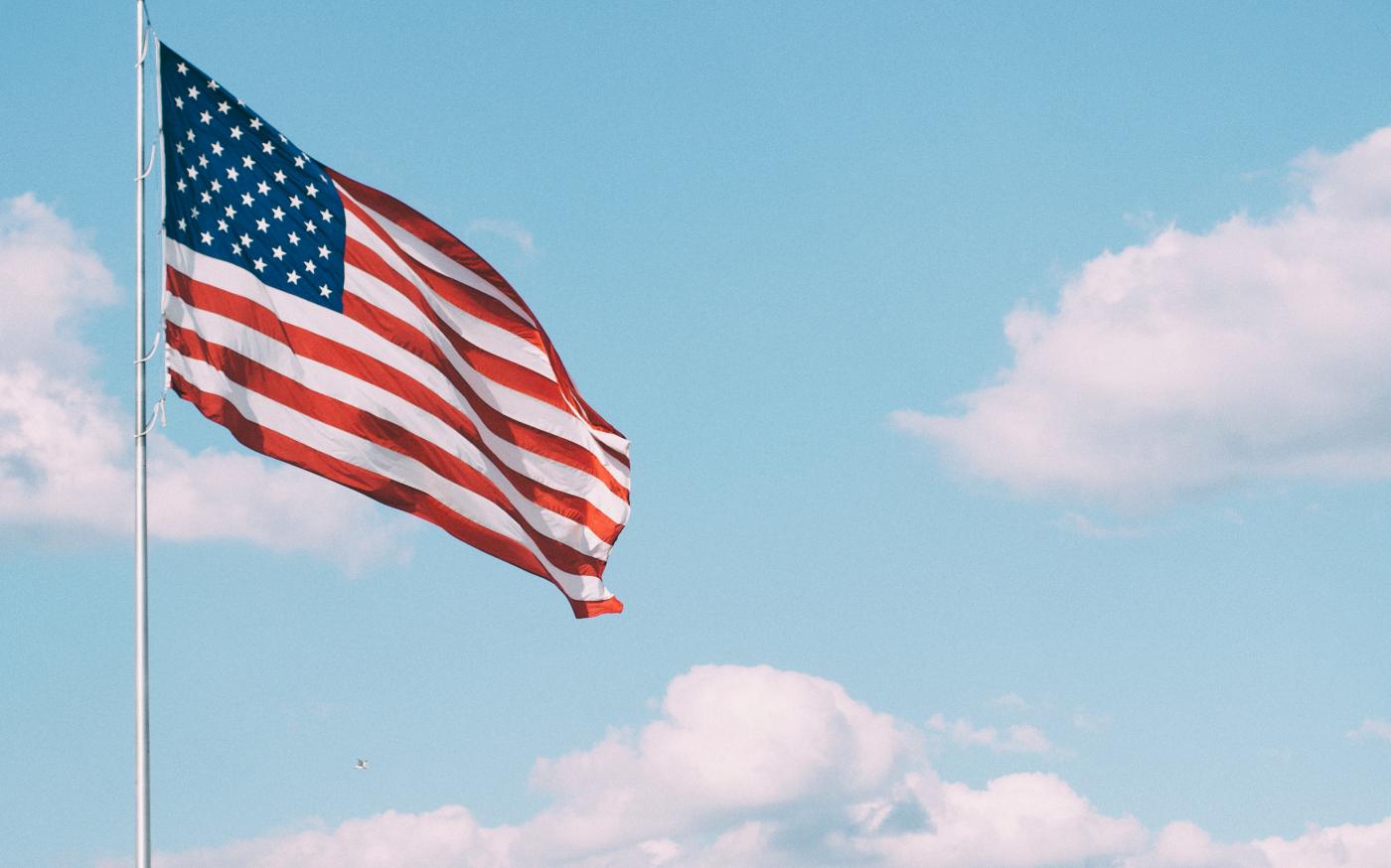 flag of U.S.A. under white clouds during daytime by Aaron Burden courtesy of Unsplash.